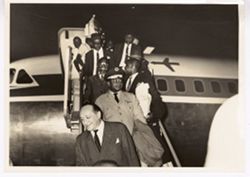 Military officials and dignitaries descend from airplane on runway
