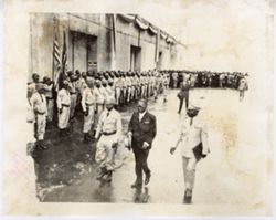 President William V. S. Tubman and military officials walk past military men in street