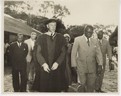 President William V. S. Tubman walks with man in cap and gown, Mrs. Tubman and group follows