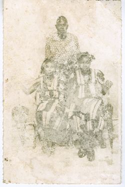 Man stands behind two seated women in matching dresses