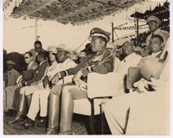 President Tubman sits on dais with dignitaries and military officials
