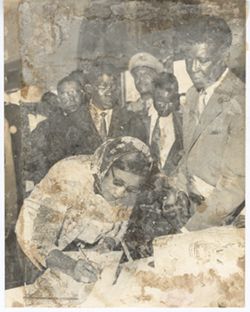Mrs. Tubman signs register as crowd waits behind her