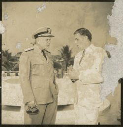 Man in military dress has dicussion with man in business suit