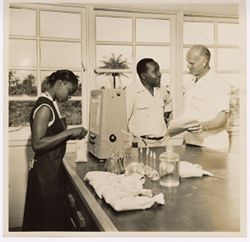 Men and woman stand around counter with scientific equipment present