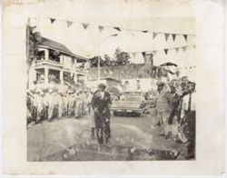 President William V. S. Tubman walks down street during a parade as military officials stand by