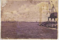 Crane jets out on rocky coastline of harbor