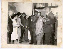 Group stands together as men shake hands