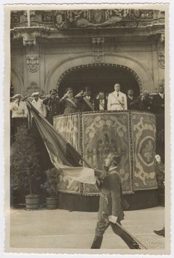 Soldier carrying a flag marches past President Tubman and other dignitaries in Spain