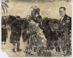 Officials in formal attire set up wreath of flowers
