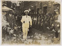 President William V. S. Tubman and man in miltary uniform walk together with troops at attention in background