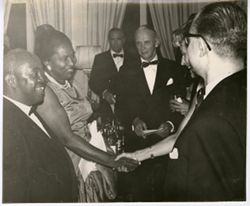Two women in formal dress shake hands