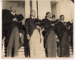 President William V. S. Tubman and other dignitaries stand with their hats over their hearts