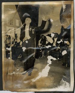 Dignitary speaks into a microphone, President Tubman and other dignitaries sit behind him