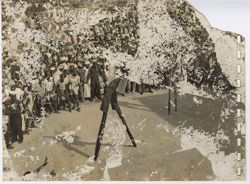 Crowd gathered around two men walking on stilts