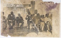 Group of men seated on stage waiting for President William V. S. Tubman to speak