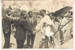 President William V. S. Tubman shakes hand of man in traditional dress as he leaves airplane