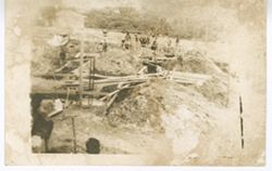 Mounds of dirt and wood at construction site with workers in background