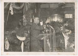 Official makes a toast at podium with microphones, including ELWA