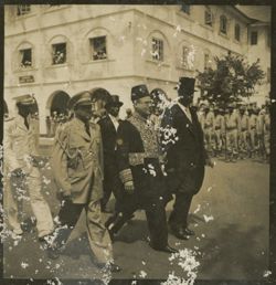 Men in formal dress, military uniform and traditional dress walk in pararde together