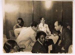 Dignitaries seated at small tables talking together