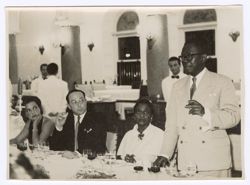 President William V. S. Tubman stands at table and makes speech while others look on