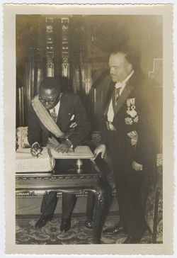 President Tubman signs a book, observed by a Spanish dignitary