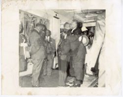 Two men in business suits hug in hallway