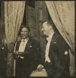 Two men stand in formal attire during a reception