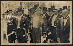 President Tubman stands with military officials and other dignitaries in formal attire