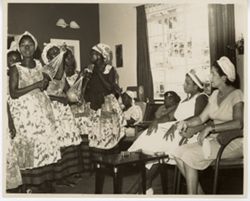 Women in matching dresses perform for group of women