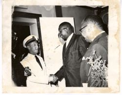 Man in white military uniform shakes hand with J. Rudolph Grimes
