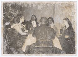 Party guests in evening wear sit at a table