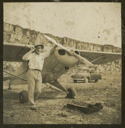 Man standing next to a small airplane touches his pith helmet