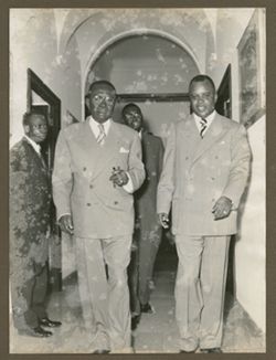 President William V. S. Tubman walks with men down hallway