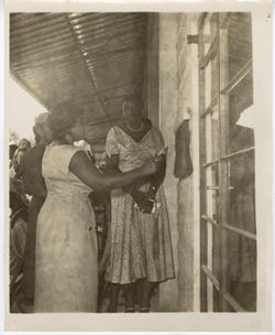 Mrs. Tubman pulls on a chord outside a building with women gathered around