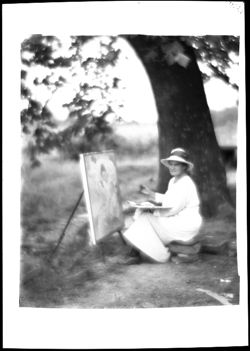 Unidentified female artist at easel near tree