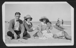 Hoagy Carmichael with two unidentified women and an unidentified man sitting on the beach.