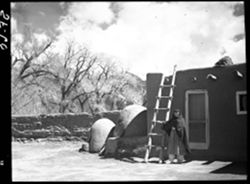 House near Governor's office, Taos Pueblo, woman near ladder