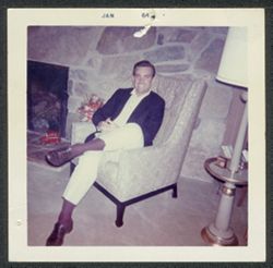 Hoagy Bix Carmichael seated next to a fireplace.