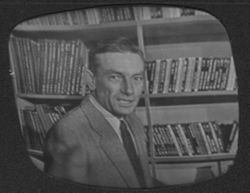 Hoagy Carmichael standing in front of bookshelves during a television show.