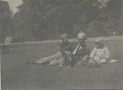 Man, two children, and dog on grass