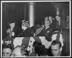Unidentified people sitting in booth draped with red, white and blue banners.