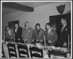 Hoagy Carmichael (4th from left) with five men standing before a dinner table at the Kappa Sigma house.