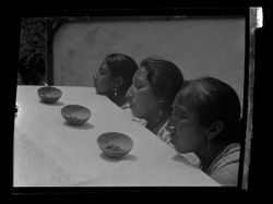 Item 0184a. Mayan funeral sequence. Two slightly different views of three Indigenous women with their chins resting on the top of the coffin. Three bowls of grain (?) in front of them.