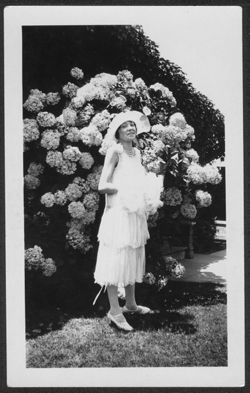 Woman posing in front of a bush.