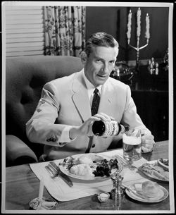Publicity photo of Hoagy Carmichael at dinner table, pouring Rheingold Lager Beer into a glass.