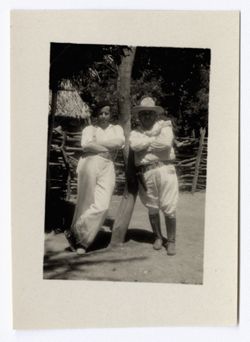 Item 1172. Eisenstein and overweight man wearing white Stetson, gun belt and knee boots leaning against a tree trunk. Thatched-roof building in background. See also Item 475 above.