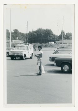 Man waving flag and holding sign in parking lot