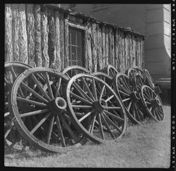 Twelve wagon wheels leaning against a pole building