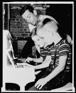 Hoagy Carmichael and his two sons, Randy and Hoagy Bix at a piano.